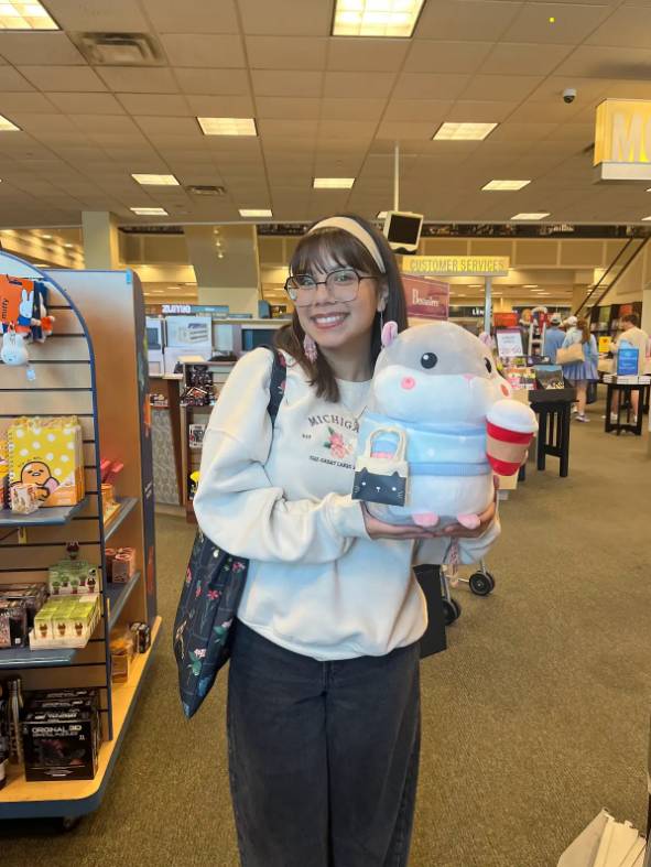 Image 1 of 2 Female student standing in a store holding stuffed animal